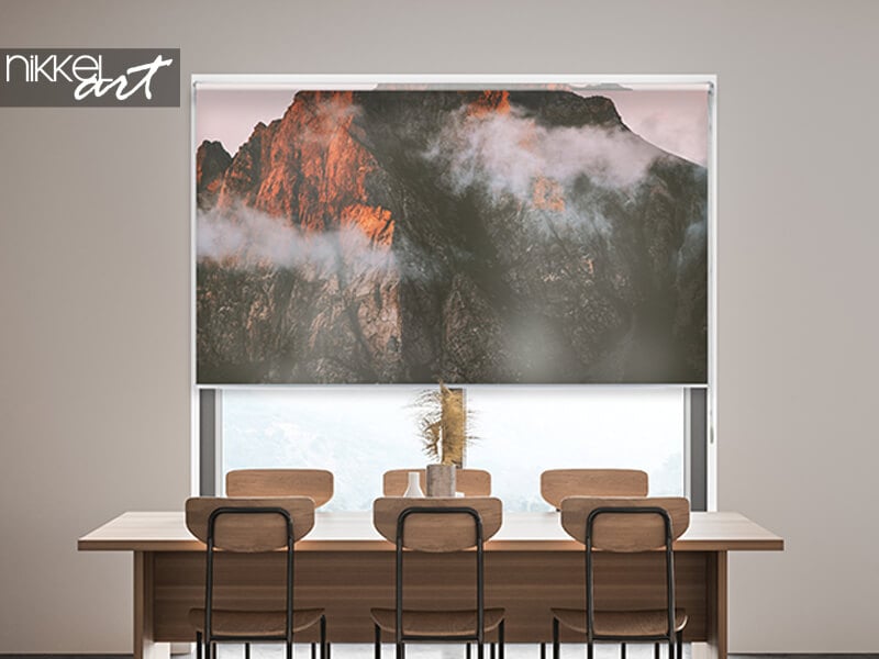 Rolgordijn met bergprint boven een eettafel, met zichtbare cassette bovenaan