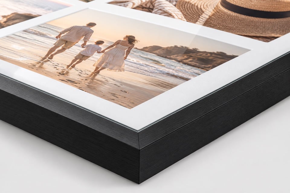 Hoek van een ingelijste fotocollage met zwarte houten lijst en wit passe-partout